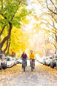 Two students ride down Greek Row in the fall, a中期 changing leaves.